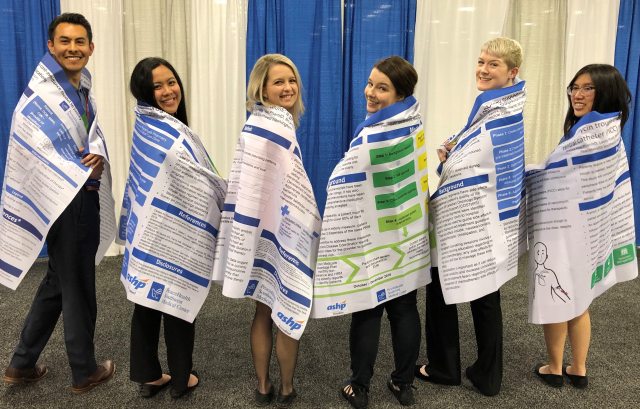 PGY1 Pharmacy Residents wear their posters as capes