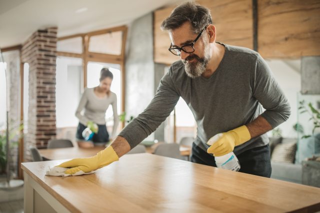 Two people wipe down counters in kitchen