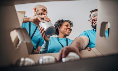 Three volunteers add food to a box