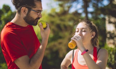 A runner eats and apple while another runner drinks juice