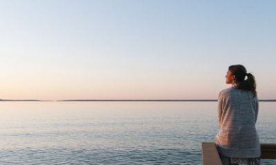 lady sitting on pier by water