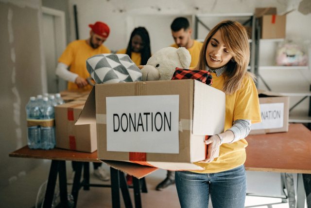 Woman carries a box marked with a sign donation