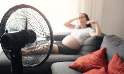 Mom-to-be sits with feet up on couch in front of a fan