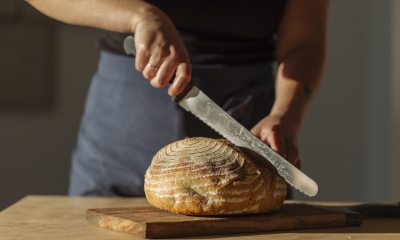 Person cutting a loaf of sourdough bread