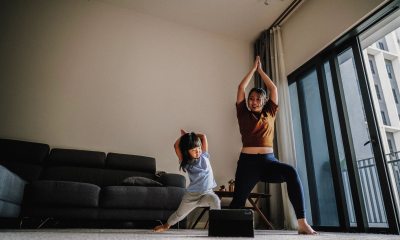 Woman and young girl lunge into yoga pose in living room