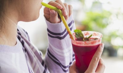 Woman drinking a red smoothie out of a glass.