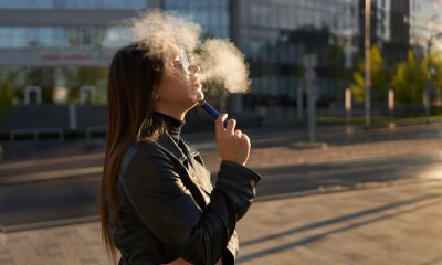 Woman uses vaping pen outside an office building