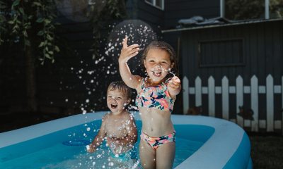 A young boy and girl splash in an inflatable backyard pool.