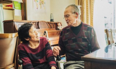 Woman in wheelchair smiles at older man sitting by a table