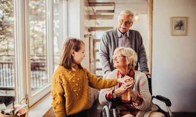 Young girl visits grandmother in wheelchair, grandfather behind