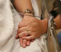A person holds the hand of a patient in a hospital bed