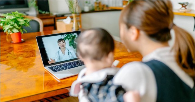 Mother sitting with child looking at computer screen for a video visit.
