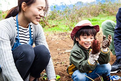 A parent and child laugh in a garden setting