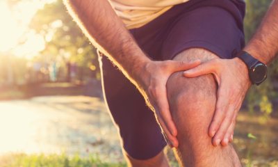 Close-up of a runner holding kne while in pain