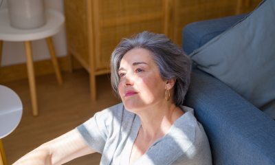 Woman with short silver hair looks up from floor into filtered sunlight 