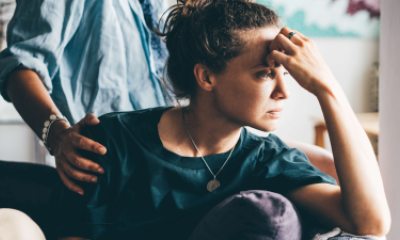 Standing woman puts comforting hand on shoulder of worried woman