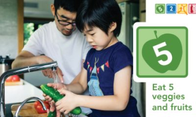 A Father and son wash a cucumber and other vegetables to prepare for eating