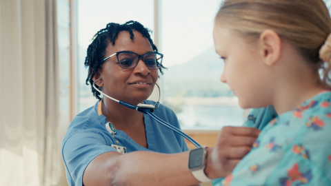 A caregiver uses a stethoscope to examine a young patient