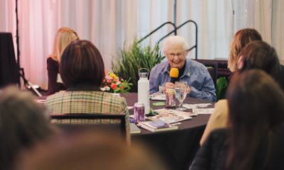 Sister Kathleen Pruitt sits at a table and smiles with other Women of Peace attendees