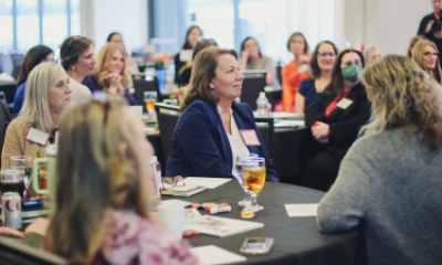 Women of Peace attendees sit at a table and listen to a speaker off camera